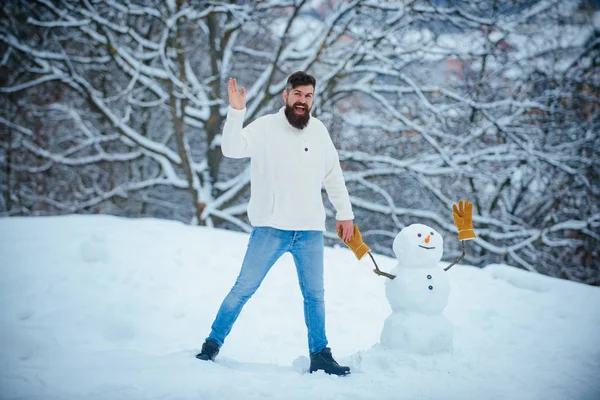 Julevinterfolk. Ung hipster vinterportrett. Vinterfølelser. Mann som leker med Snowman - isolert på snøbakgrunn. Morsomme vintermennesker Portrett . – stockfoto