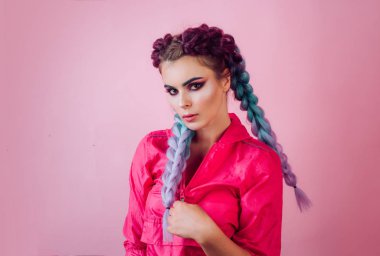 Saçına renkli kanekalon örülmüş güzel bir kız. Renkli mor ombre saçlı ve profesyonel makyajlı güzel bir kadın pembe arka planda izole edilmiş. Kuaför salonu konsepti.