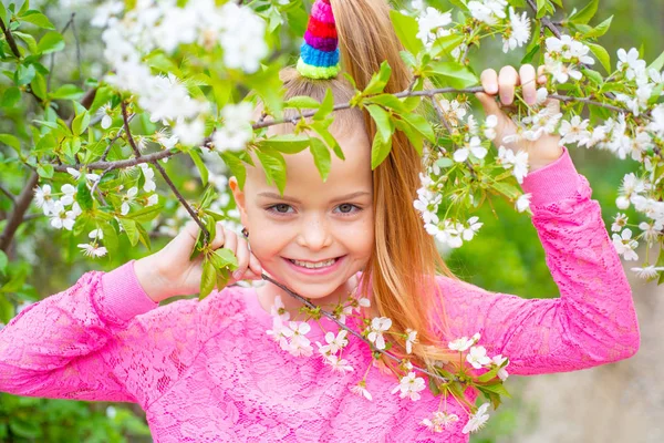 Menina caucasiana de sete anos em um parque sorrindo para a câmera. Conceito de primavera. Caminhe num parque. Atividades Férias . — Fotografia de Stock