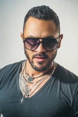 Güneş gözlüklü yakışıklı bir adam. Erkek yüzü. Yakışıklı, erkeksi bir adamın portresi. Gri duvara karşı memnun iş adamının portresi. Güneş gözlüğü. Şehir modası.