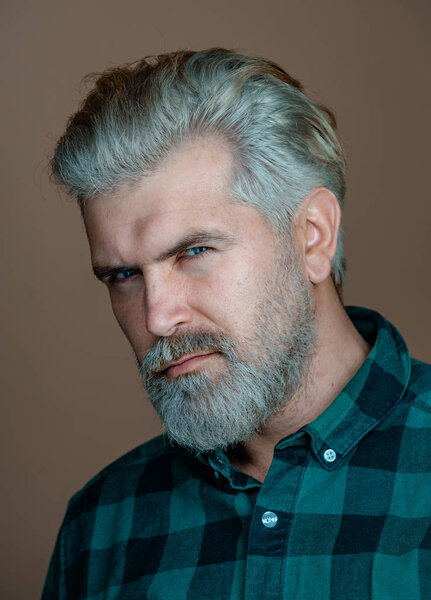 Mature blonde bearded guy with trendy hairdo in casual shirt smiling and looking in camera. Close up portrait of a very handsome man.