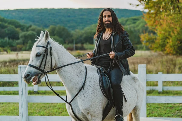 Handsome rider man on horse. Equestrian rides his white well looking horse. Handsome man riding horse at farm. Attractive male sitting on white stallion on the ranch in autumn. — 스톡 사진