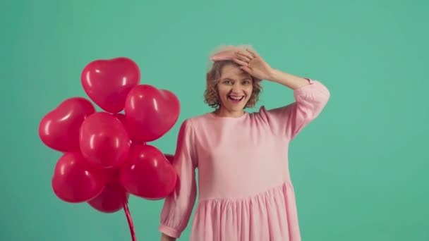 Valentine Beauté fille avec des ballons à air rouge riant, sur fond vert. Belle jeune femme heureuse. Fête de vacances. Modèle joyeux posant, s'amusant, célébrant la Saint-Valentin . — Video