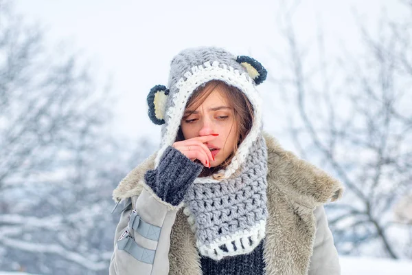 Gripe fría temporada de invierno, secreción nasal. Mostrando a una mujer enferma estornudando en el parque de invierno . — Foto de Stock