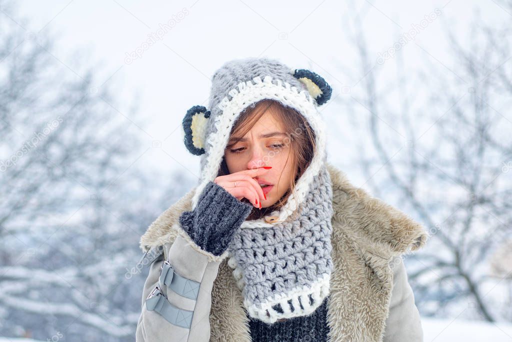 Cold flu winter season, runny nose. Showing sick woman sneezing at winter park.