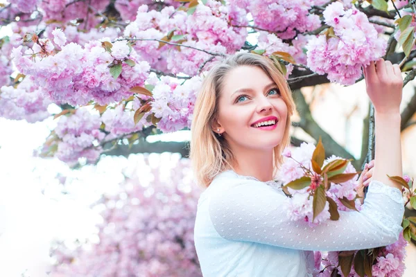 Mooie vrouw met bloeiende Sakura boom en zonnige dag. — Stockfoto