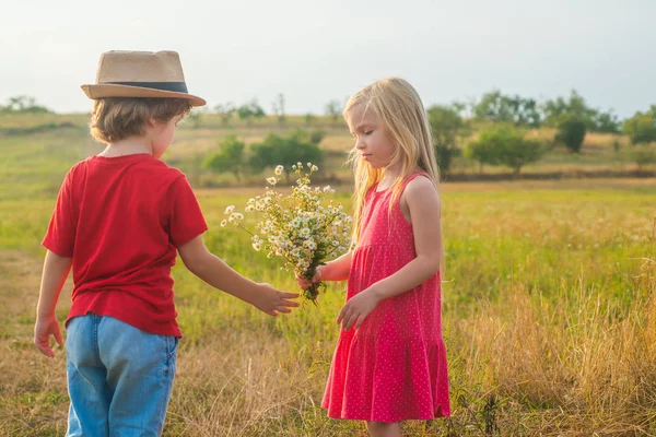 幼少期のコンセプト。甘い天使の子供たち田舎の子供時代バレンタインデー。愛だ人間の感情-子供の最初の愛。幸せな子供の女の子と男の子抱擁上の牧草地で夏に自然. — ストック写真