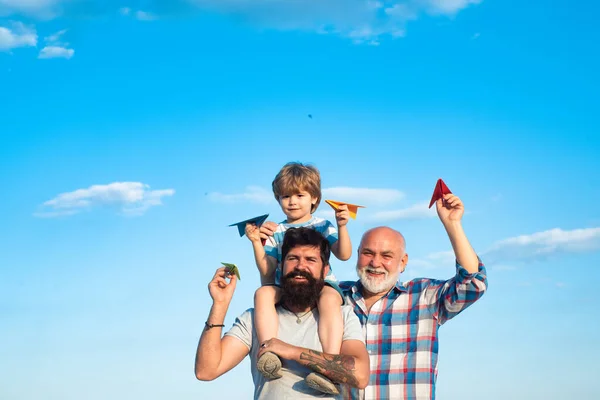 青空と雲の背景におもちゃの紙飛行機で幸せな祖父と孫。幸せな男は家族を愛してるお父様とお祖父様がリラックスして. — ストック写真