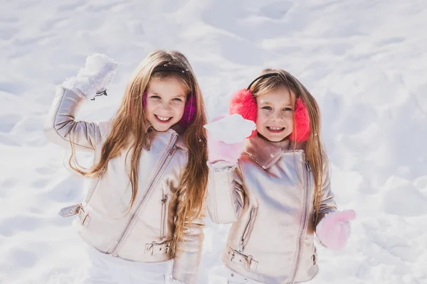 Niño de invierno. Retrato de dos niñas jugando con nieve en invierno. Niños en Parque de Invierno jugando bolas de nieve . —  Fotos de Stock