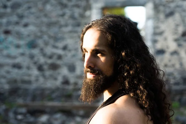 Hombre barbudo guapo con el pelo largo y oscuro. Estilo de hombre y concepto de moda. Primer plano retrato del hombre guapo con el pelo largo y oscuro ondulado y la barba. Hombre confiado con apariencia inusual mirada recta —  Fotos de Stock