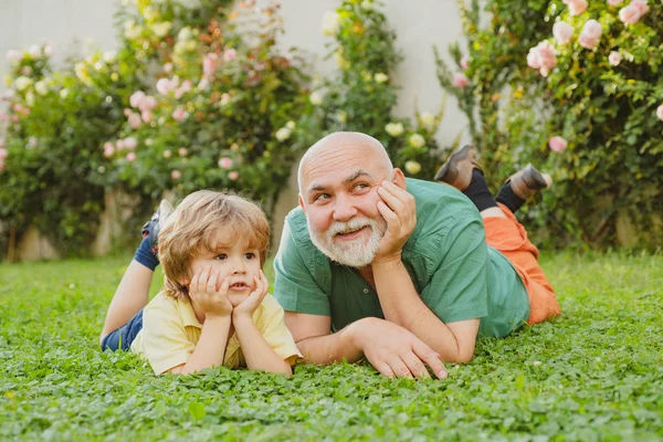 Two different generations ages: grandfather and grandson together. Happy loving family. Happy grandfather and child grandson laugh and have fun together in summer in nature. — Stock Photo, Image