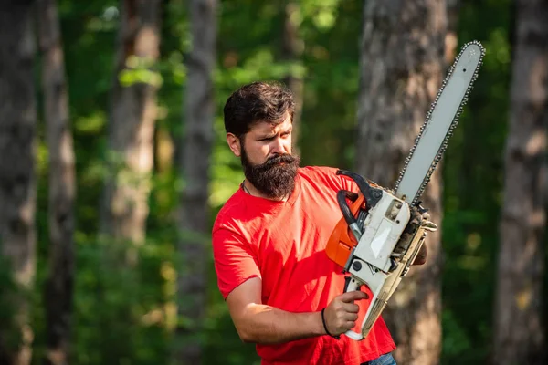 Lumberjack worker with chainsaw in the forest. Lumberjack in the woods with chainsaw axe. Lumberjack with chainsaw on forest background. — Stock Photo, Image