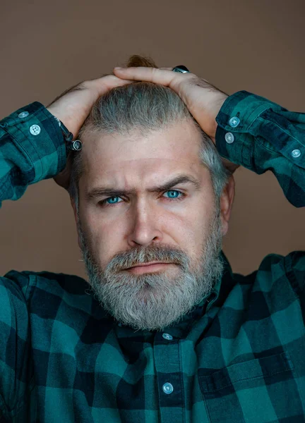 Porträt eines selbstbewussten Mannes. schöner Hipster-Mann mit Bart blickt vor grauem Hintergrund in die Kamera. — Stockfoto