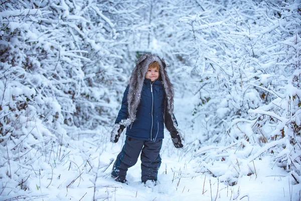 Invierno en el campo. Ropa de invierno para niños. Niño jugando en el campo cubierto de nieve en el bosque de invierno. El concepto de la bondad del niño de invierno y la infancia . — Foto de Stock