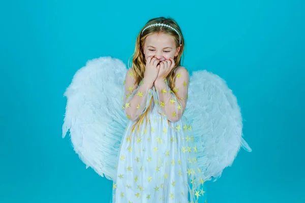 Día de San Valentín. Parece un ángel. Niño ángel con el pelo rubio rizado. Linda niña en vestido blanco de pie sobre el fondo de color. Retrato de hermosa niña ángel con alas de ángeles . — Foto de Stock