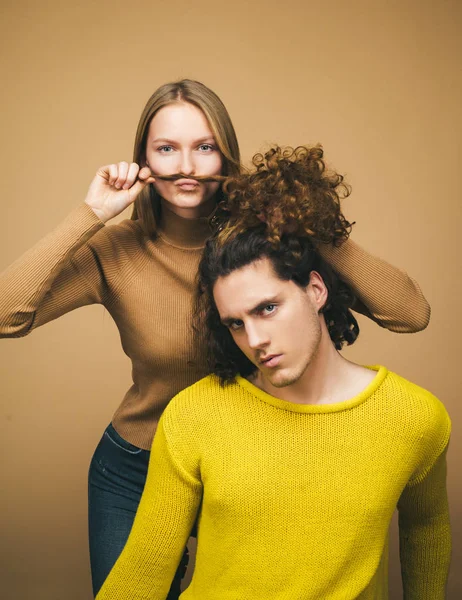 Belle fille jouant avec les cheveux de son petit ami. Différents types de concept de cheveux. Joyeux couple en photo studio amoureux. bel homme avec de longs cheveux ondulés et sa mignonne petite amie . — Photo