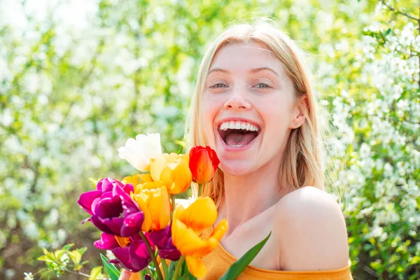 快乐的女人在郁金香地里放松。 妇女日，3月8日。 五彩缤纷的鲜红郁金香. — 图库照片