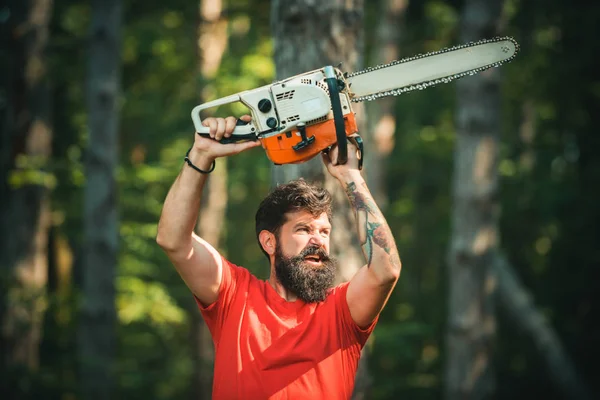 Lumberjack in the woods with chainsaw axe. Handsome young man with axe near forest. Chainsaw. Deforestation. Lumberjack worker with chainsaw in the forest. — 스톡 사진