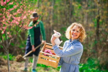 Bahar. Kadın ve tavşan. Küçük kız Paskalya yumurtası avında eğleniyor..