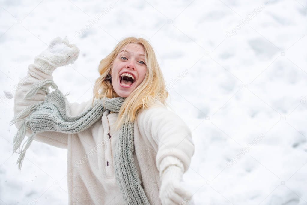 Portrait of a excited woman in the winter. Cheerful girl outdoors. Happy young girl playing snowball fight. Snowball. Happy woman holds snowball in hands.
