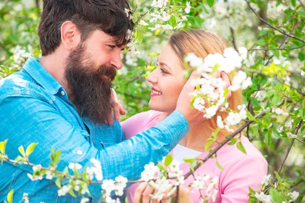 Giovane coppia felice vicino all'albero dei fiori. Gli amanti su una passeggiata in un parco fiorito di primavera. Amare uomo e donna in una passeggiata in un parco fiorito primaverile . — Foto Stock