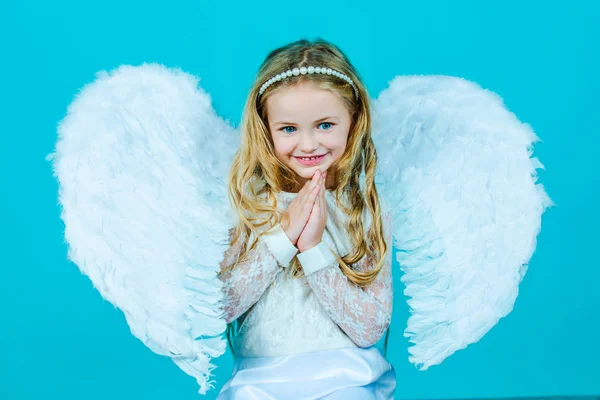 Valentinstag. Engel. schelmisches kleines Engelmädchen, das mit geballten Fäusten steht. Engel kleine Hände für dich gekreuzt. — Stockfoto