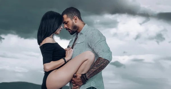 Duygusal bir kadın dramatik gri arka planda vahşi bir adama bacağını kaldırıyor. Gökyüzüne karşı güzel bir çift. Çiftler dışarıda romantik bir yürüyüş yapar. Gerçek aşk konsepti.