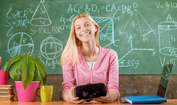 学校の教室の机に座ってレッスンを受けているかなり笑顔のブロンドの女の子。幸せな10代の生徒は新しい知識を得る。学校に戻る。9月1日. — ストック写真