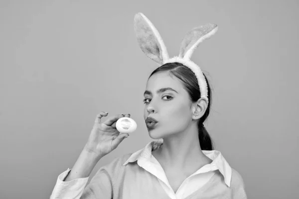 Lippen en Pasen, lippenstift kus afdruk op paasei. Vrolijk Pasen. Jonge vrouw in konijn bunny oren. Portret van een gelukkige vrouw in bunny oren. Eieren zoeken. — Stockfoto