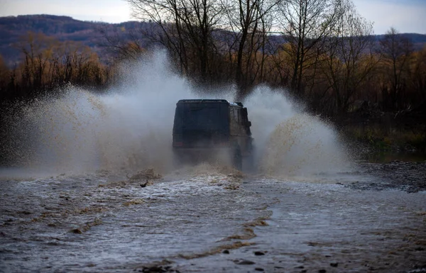 Driver competing in an off-road 4x4 competition. Car wheels on steppe terrain splashing with dirt. Dirty car drive on high speed. SUV or off-roader on mud road. Expedition off roader. — 스톡 사진