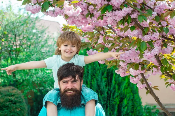 Felice giorno dei padri. Ragazzo con padre che si diverte insieme nel parco. Felice padre dando spalla giro sulle spalle in giardino . — Foto Stock