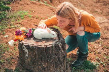 Komik Paskalya tavşanı. Küçük kız Paskalya yumurtası avında eğleniyor. Mutlu gülümseyen küçük kız tavşanla paskalya yumurtası avlıyor..