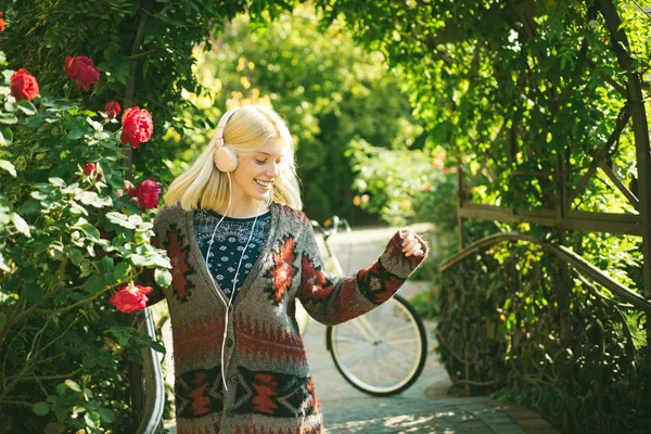 Primer plano retrato de una hermosa chica en suéter caliente y auriculares de pie cerca de hojas de otoño de colores. Obra de arte de mujer romántica. Bonita ternura modelo mirando a la cámara . —  Fotos de Stock