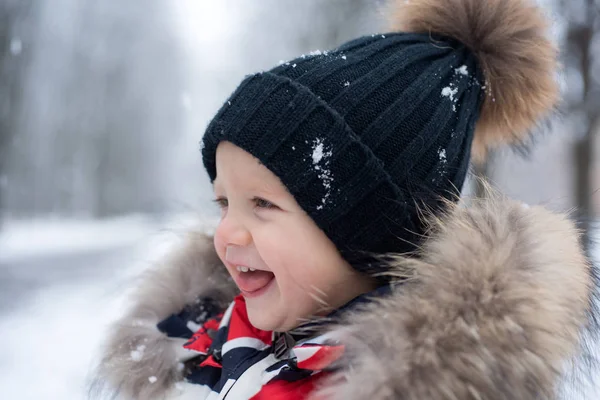 Emotionaler kleiner Junge bei einem Spaziergang im Winterpark. Junge zu Fuß Schneefall. Nahaufnahme. positives Kind. kleiner Junge, der draußen posiert. glückliches kleines Kind lächelnd. er spielt an einem Wintertag draußen. — Stockfoto