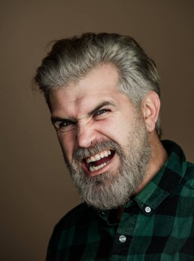Kızgın Adam. Gri arka planda mutlu bir adamın portresi. Yakışıklı bir adamın moda tarzı portresi. Gri arka plandaki yakışıklı genç adam kameraya bakıyor..