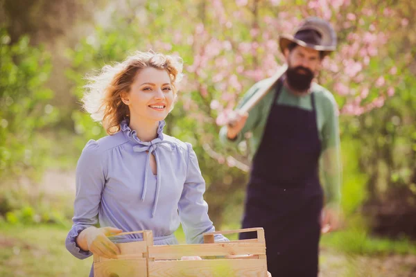 Ritratto di coppia di fattorie che lavorano in giardino insieme. Immagine di due contadini felici con gli strumenti. Giovane coppia giardinaggio in giardino . — Foto Stock