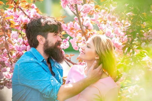 Çiçek açan bahçedeki kadın ve erkek. Bahar çiçekli arka planda gülümseyen genç bir çiftin portresi. Sakura ağacının yanında bir çift. Mutlu Paskalyalar. — Stok fotoğraf