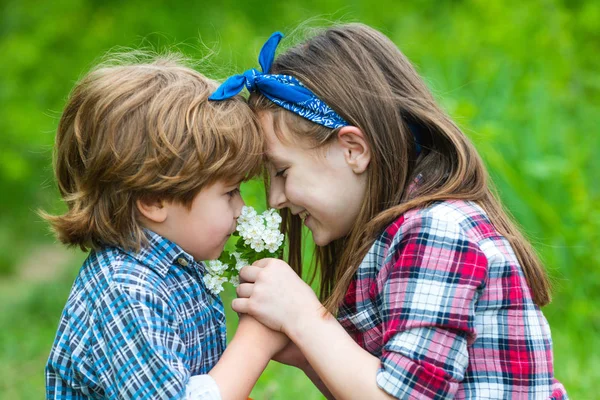 子供たち女の子と男の子吹いてタンポポの花で緑の牧草地屋外. — ストック写真