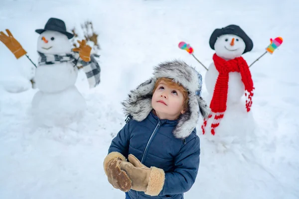Enfant heureux jouant avec boule de neige sur fond blanc d'hiver. Portrait d'hiver d'enfant mignon dans la neige Jardin . — Photo