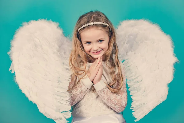 Schönes kleines Engelmädchen. schelmisches kleines Engelmädchen, das mit geballten Fäusten steht. schönes kleines Engelmädchen, das wie im Gebet mit den Armen vor der Brust steht. — Stockfoto