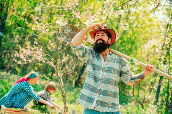 Día de los padres. Familia feliz: padre en el fondo del jardín de primavera. Hermosa joven sonriente familia divirtiéndose en el patio de la granja. Caminata familiar en el campo agrícola . —  Fotos de Stock