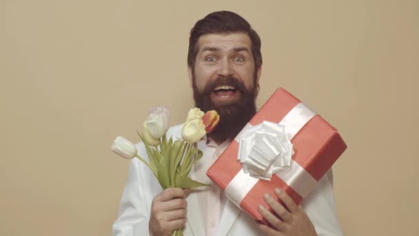 Walentynki, Dzień Kobiet, urodziny. Mężczyzna z prezentem i bukietem tulipanów na urodziny. Romantyczny mężczyzna. Brodaty mężczyzna trzymać bukiet kwiatów i pudełko prezentów. — Wideo stockowe