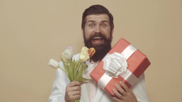 Dia dos Namorados, Dia das Mulheres, aniversário. Homem com presente e buquê de tulipas para o aniversário. Homem romântico. Homem barbudo segurar buquê de flores e caixa de presente . — Vídeo de Stock