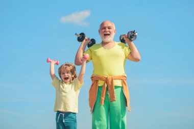 Yaşlı olgun bir adam ve küçük bir çocuk halterle egzersiz yapıyor. Spor ve eğitim kavramları. Sağlıklı yaşam ve spor kavramı.