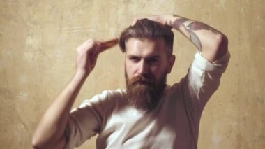 Sabah rutini. Saçını tarayan yakışıklı genç sakallı adam. Sakallı adam saçını tarıyor.