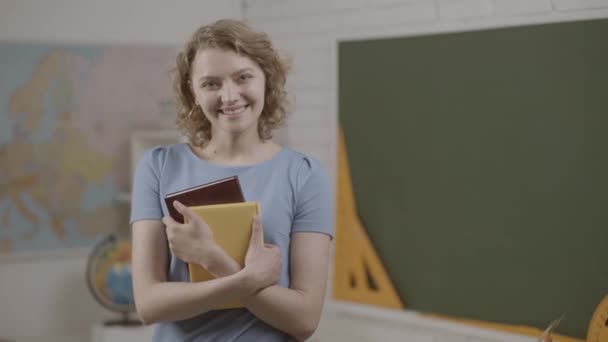 Uczennica lub nauczycielka trzymająca książki w klasie. Gotowy do szkoły. Uśmiechnięta wykładowczyni w klasie. Pomocny nauczyciel. — Wideo stockowe