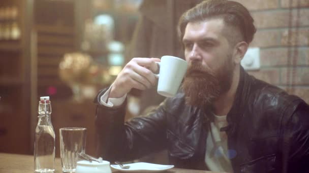 Een man met baard in een café. Serieuze man die een kop koffie drinkt in het café. Zelfverzekerde succesvolle man ontspannen in de buitenlucht cafe op zoek duur. Man drinkt expresso koffie — Stockvideo
