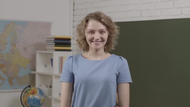 Divertente giovane insegnante donna in classe. Una docente sorridente in classe. Insegnante utile. Educazione. Moderno insegnante attraente . — Video Stock