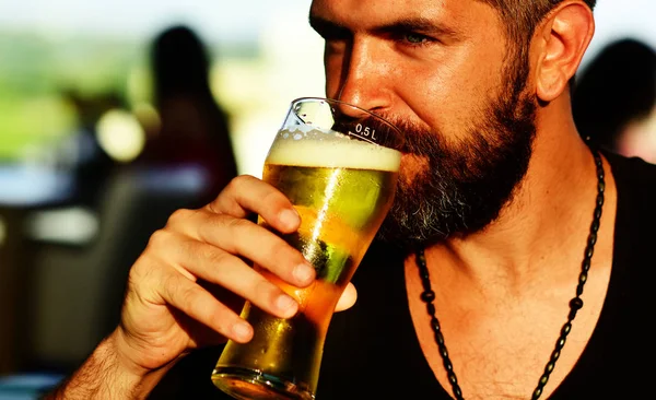 Bearded man drinking lager beer. Senior man drinking beer with surprise face. Man holds glass of beer.