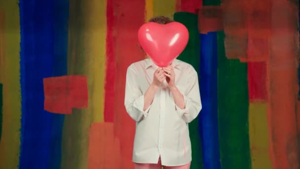 Funny girl with red heart balloon. Beauty girl with colorful air balloons laughing over rainbow background. — Stok video